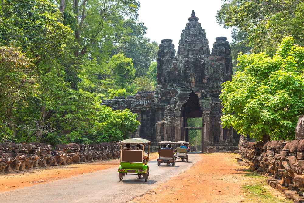 Des tuk-tuks transportant des passagers à travers la porte nord d'Angkor Thom